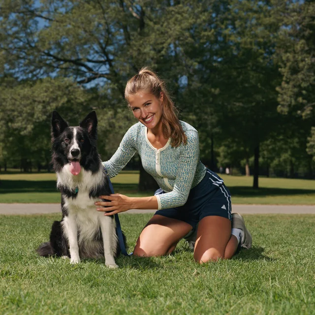 Opiekunka siedzi na trawie obok border collie